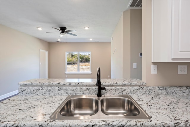 kitchen with white cabinetry, light stone countertops, sink, and ceiling fan