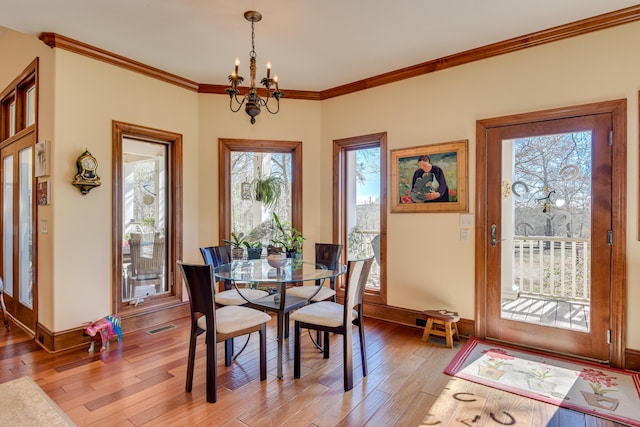 dining room featuring hardwood / wood-style flooring, ornamental molding, and a chandelier