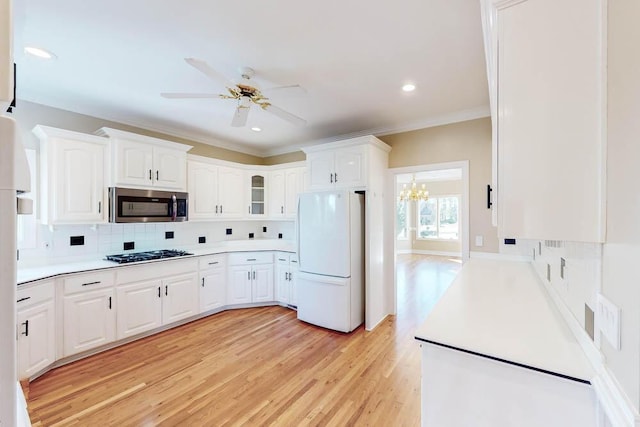 kitchen with decorative backsplash, white cabinetry, light hardwood / wood-style flooring, and appliances with stainless steel finishes