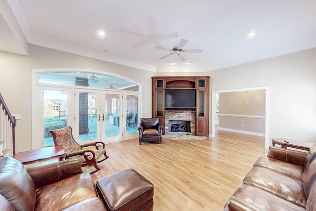 living room with ceiling fan, french doors, a stone fireplace, crown molding, and wood-type flooring