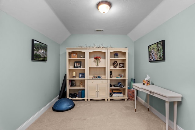 interior space with vaulted ceiling, baseboards, light colored carpet, and visible vents