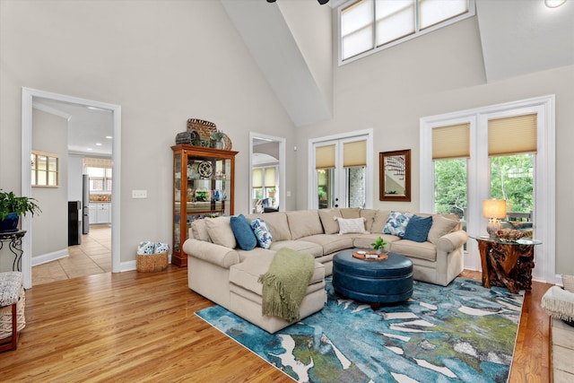 living room with high vaulted ceiling, baseboards, and wood finished floors