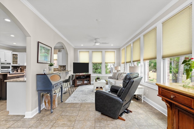 living area with crown molding, a ceiling fan, and a healthy amount of sunlight