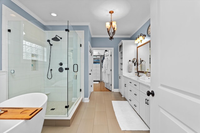 full bath featuring crown molding, a notable chandelier, vanity, a freestanding tub, and a shower stall