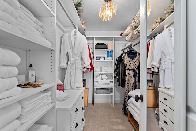spacious closet featuring an inviting chandelier and light carpet