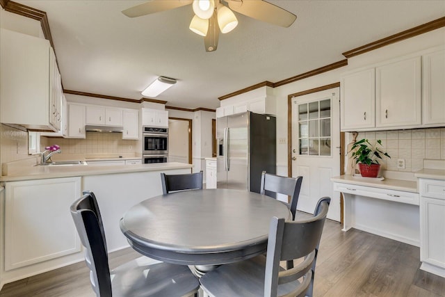 dining room with dark wood finished floors, a ceiling fan, and ornamental molding