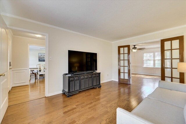 living area featuring a decorative wall, french doors, light wood-type flooring, and ornamental molding