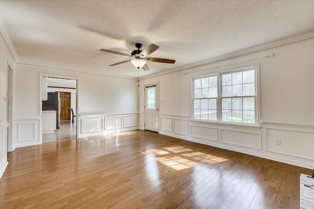 empty room with a textured ceiling, crown molding, a ceiling fan, and wood finished floors