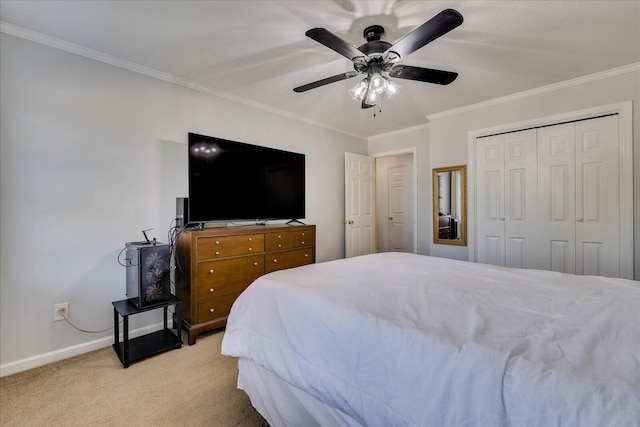 bedroom featuring a ceiling fan, a closet, crown molding, baseboards, and light colored carpet