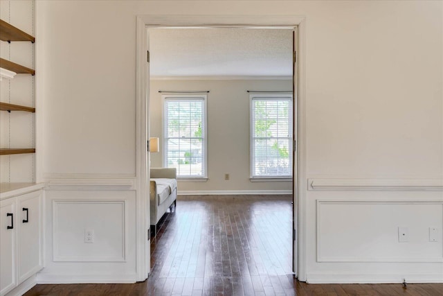 interior space featuring a textured ceiling, crown molding, baseboards, and dark wood-style flooring