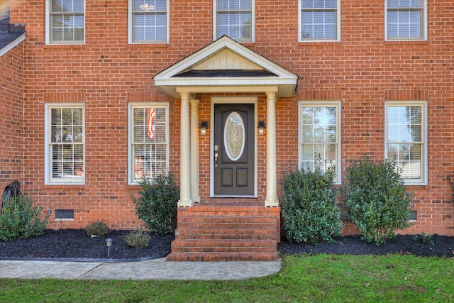 view of exterior entry featuring crawl space and brick siding