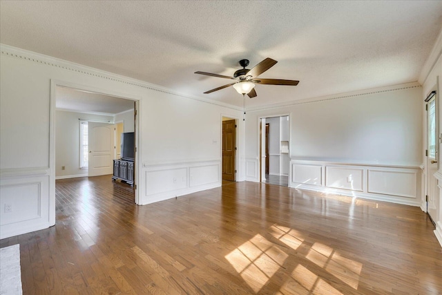 empty room with ornamental molding, a textured ceiling, ceiling fan, and wood finished floors