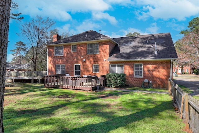 back of house with a lawn, fence, a wooden deck, brick siding, and a chimney