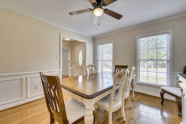 dining room with light wood-style flooring, plenty of natural light, wainscoting, and a textured ceiling