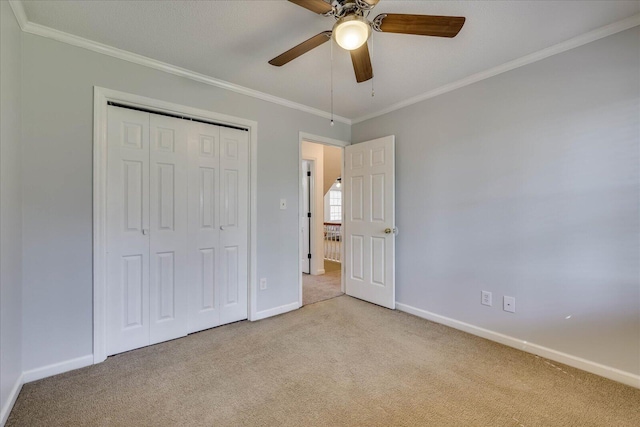 unfurnished bedroom featuring crown molding, carpet, baseboards, and a closet