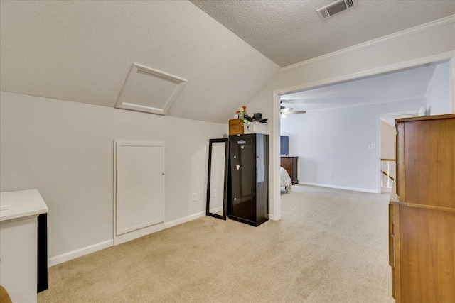 additional living space with visible vents, attic access, vaulted ceiling, carpet floors, and a textured ceiling