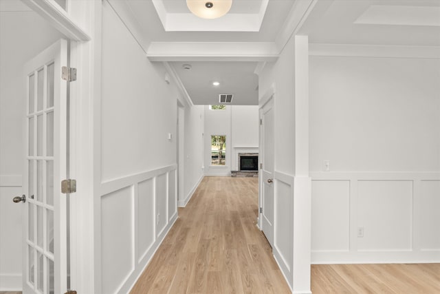 corridor with light hardwood / wood-style floors and ornamental molding