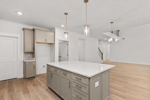 kitchen with pendant lighting, gray cabinets, light hardwood / wood-style flooring, and a kitchen island