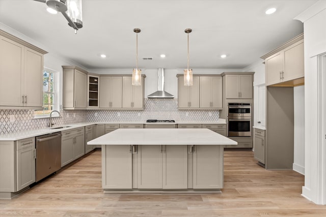 kitchen with light hardwood / wood-style flooring, wall chimney exhaust hood, gray cabinets, appliances with stainless steel finishes, and a kitchen island