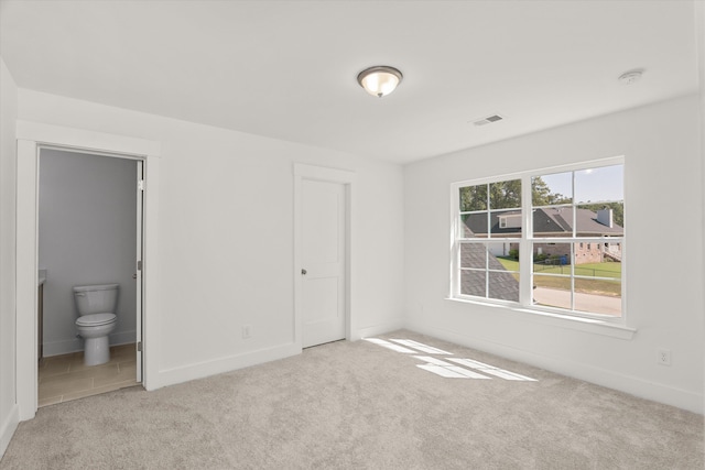 unfurnished bedroom featuring connected bathroom and light colored carpet