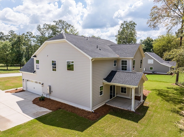 rear view of house featuring a garage, a yard, and a patio