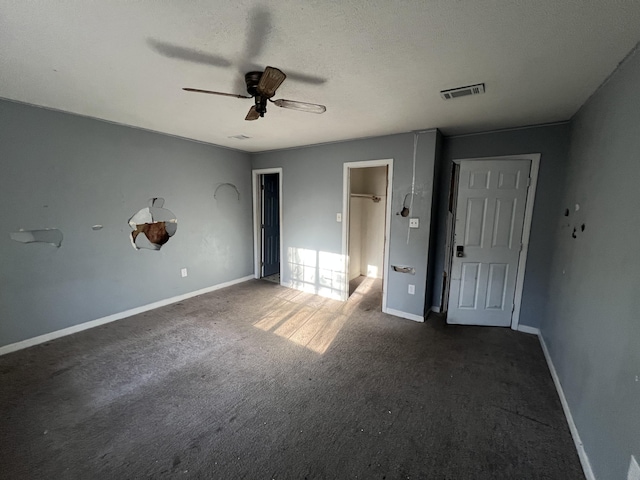 unfurnished bedroom with ceiling fan, dark carpet, and a textured ceiling