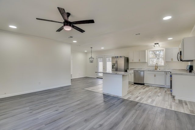 kitchen featuring white cabinets, a kitchen island, stainless steel appliances, light hardwood / wood-style floors, and sink