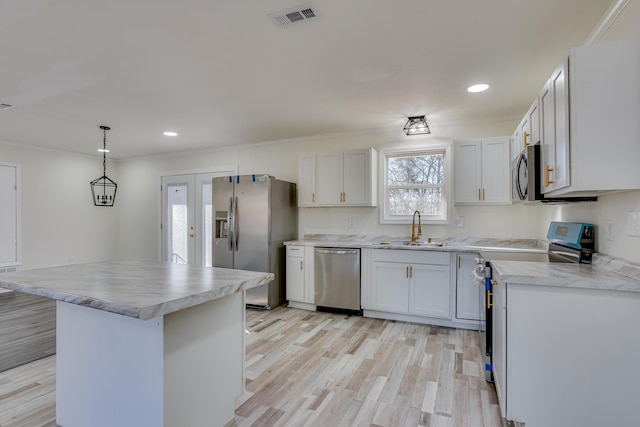 kitchen with sink, white cabinets, appliances with stainless steel finishes, and hanging light fixtures