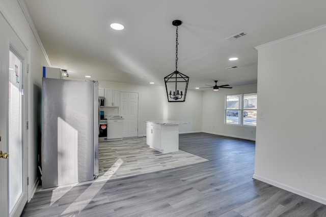 unfurnished dining area with ceiling fan with notable chandelier, ornamental molding, and light wood-type flooring