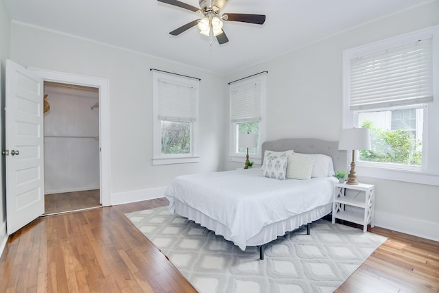 bedroom with baseboards, a ceiling fan, hardwood / wood-style flooring, and multiple windows