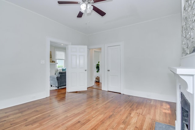 unfurnished living room featuring a fireplace with flush hearth, ceiling fan, and hardwood / wood-style flooring