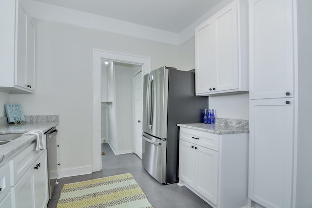 kitchen with concrete flooring, white cabinetry, stainless steel appliances, and baseboards