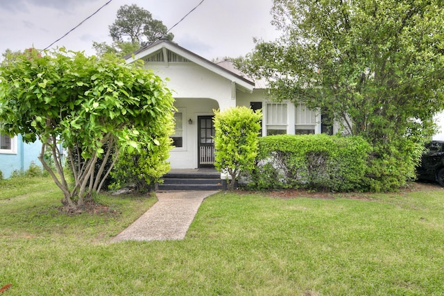 view of front of house with a porch, a front lawn, and stucco siding