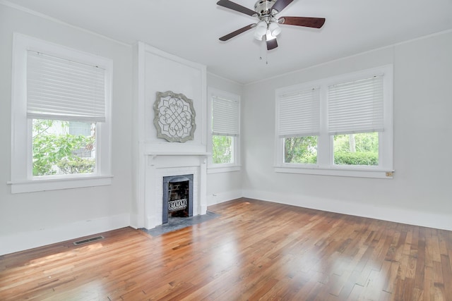 unfurnished living room featuring wood-type flooring, visible vents, a ceiling fan, and a fireplace