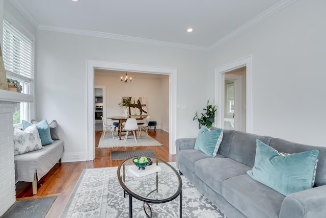 living area with wood finished floors, recessed lighting, a notable chandelier, and ornamental molding