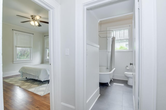 bathroom featuring a freestanding tub, crown molding, a wealth of natural light, and wainscoting