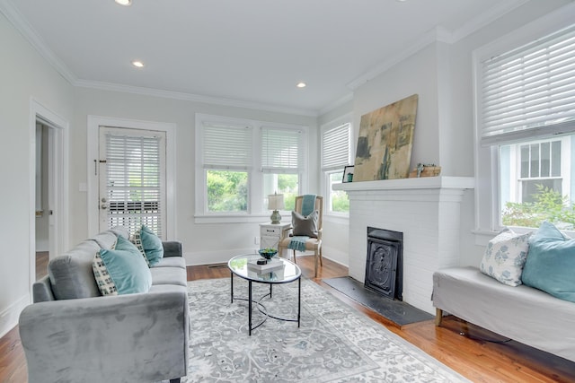 living room featuring baseboards, a brick fireplace, wood finished floors, and ornamental molding