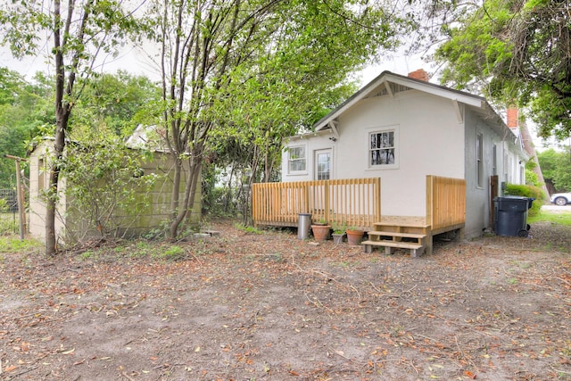 back of property with a chimney and a deck