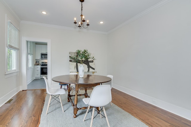 dining area featuring wood finished floors, a chandelier, and ornamental molding