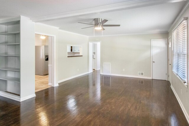 spare room with built in shelves, a wealth of natural light, crown molding, and ceiling fan