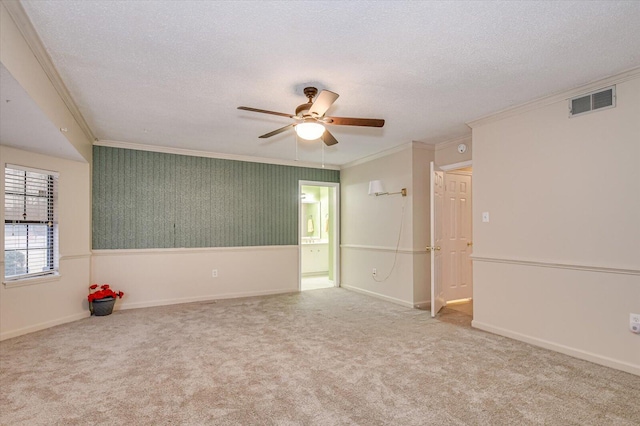 empty room featuring visible vents, carpet floors, a textured ceiling, and crown molding