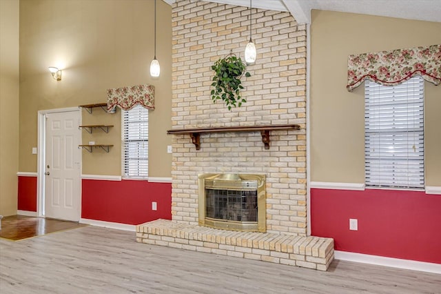 unfurnished living room with a brick fireplace, high vaulted ceiling, baseboards, and wood finished floors