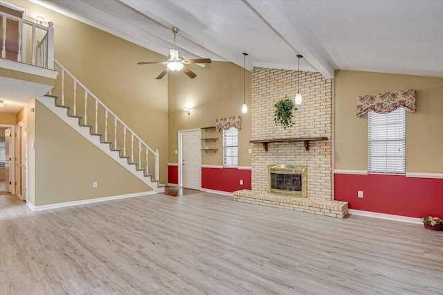 unfurnished living room featuring stairway, beamed ceiling, wood finished floors, and a fireplace