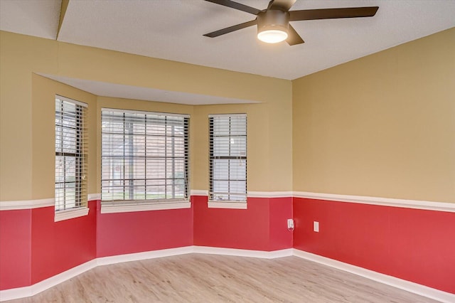 spare room featuring a textured ceiling, wood finished floors, baseboards, and ceiling fan