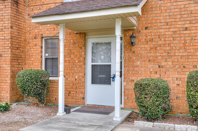 entrance to property with brick siding and roof with shingles