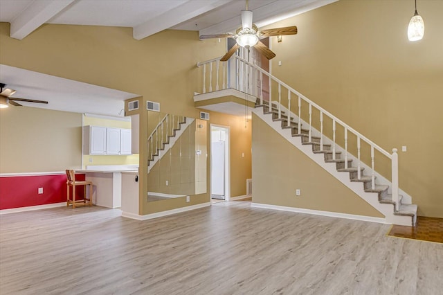 unfurnished living room featuring stairway, visible vents, light wood finished floors, and ceiling fan