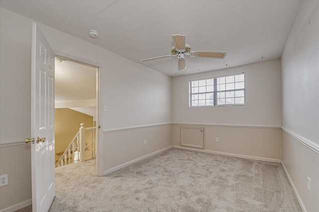 carpeted empty room with ceiling fan and baseboards