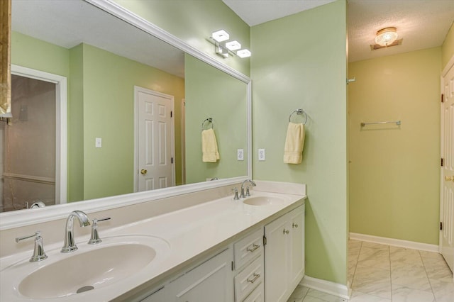 full bath with double vanity, marble finish floor, baseboards, and a sink