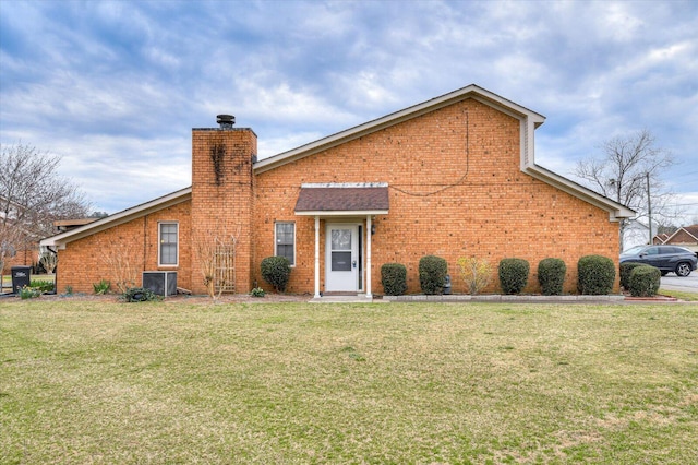 view of front of home featuring brick siding, central AC, a chimney, and a front lawn