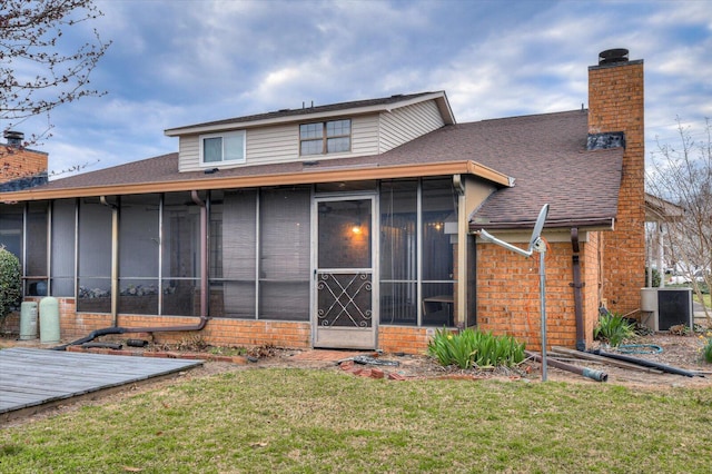 back of property with a yard, brick siding, a sunroom, and a chimney